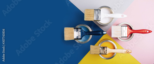 Fotografía Banner with four open cans of paint with brushes on them on bright symmetry background