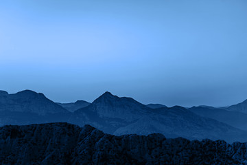Beautiful dark blue mountain landscape with visible contrast on blue sky. Classic blue color of the year 2020.
