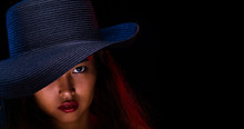 Fashion Young Tan Skin Asian Girl Long Curly Hair Red Lip And Dress Wear Dark Navy Blue Hat Pose Arm And Hand Portrait Style. Studio Lighting Black Background Isolated Copyspace Close Up