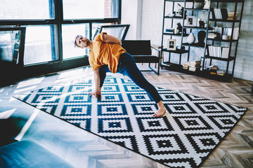 Fototapete - Focused adult man exercising yoga in flat
