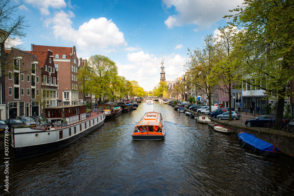 Obraz na płótnie Amsterdam canal with cruise ship with Netherlands traditional house in Amsterdam, Netherlands. Landscape and culture travel, or historical building and sightseeing concept. w salonie