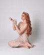 © faestock - full length portrait of a pretty, fairy girl wearing a nude flowy dress and crystal crown. Seated pose against a grey studio background.
