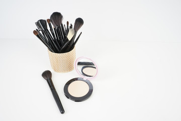 Wall Mural - A set of a black make up brushes inside a wooden busket over the white background