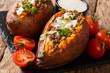Whole baked sweet potato with lentils served with sour cream and tomatoes close-up on a slate board. horizontal