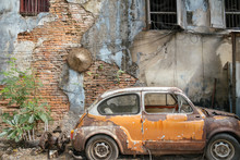 Bangkok,Thailand. November 30,2019 : Abandoned Wrecked Orange Vintage Car Against Old Brick Wall Background.