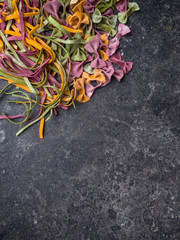 Wall Mural - Homemade pasta, farfalle bow-tie, fettuccine or tagliatelle colorful pasta on grey background with flour, Colorful butterfly pasta. Italy ingredients for lunch.