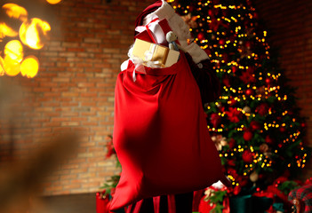 Wall Mural - Santa Claus holding bag full of Christmas gifts in room