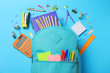 Stylish backpack with different school stationery on light blue background, flat lay