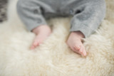 Fototapeta  - A beautiful soft delicate warm young baby foot photographed with a shallow depth of field. gentle calm colours and feel. baby care and well being. babies feet on a cream fur rug.