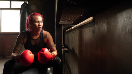 Asian woman sitting after doing boxing at the gym.