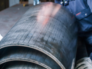 An apprentice factory metal engineer welder checking the condition of the steel cut parts ready to be sent out of a factory to clients. quality control industrial