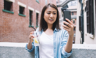 Wall Mural - Happy Asian female tourist taking selfie and smiling