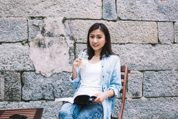 Wall Mural - Joyful Asian modern woman reading book on street