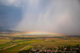 Fototapeta Tęcza - Nice combination of a storm and a rainbow in the summer. Vibrant colors in the sky.