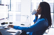 © BullRun - Busy African American woman drinking coffee while working with computer