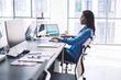 © BullRun - Elegant pleased ethnic woman working at computer in office