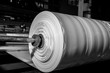 © josh - B&W imagery of spool of plastic packaging sheet heavy duty for industrial use outdoors. wrapped around a metal pole ready to feed into a machine for cutting into shape or printing logos or branding