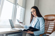 © Petryshak - Successful small business owner. Beautiful young businesswoman using laptop and doing some paperwork while working on laptop.