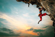 Leinwandbild Motiv Athletic Woman climbing on overhanging cliff rock with sunset sky background.