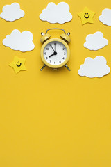 Wall Mural - Yellow round alarm clock, moon, stars and white clouds on the yellow background.