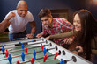 Multiethnic group of young friend having fun at beer pub, playing table soccer