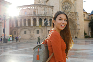 Wall Mural - Portrait of beautiful tourist woman in Valencia with Cathedral on the background. Smiling traveler girl with Valencia landmark in Spain.