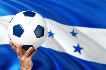 Honduras soccer concept. National team player hand holding soccer ball with country flag background. Copy space for text.