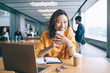 © BullRun - Portrait of cheerful Asian female blogger with cellphone gadget in hands smiling at camera during e learning time, successful Chinese woman rejoicing near desktop with modern laptop computer