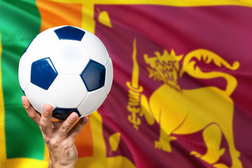 Sri Lanka soccer concept. National team player hand holding soccer ball with country flag background. Copy space for text.