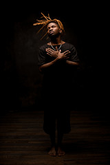 Canvas Print - Black man with blonde dreadlocks posing in the action standing barefoot