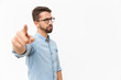 © Mangostar - Strict frowning guy in eyewear pointing finger at camera. Handsome young man in casual shirt and glasses standing isolated over white background. Firing concept