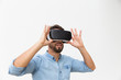© Mangostar - Bearded male user in VR glasses enjoying experience. Young man in virtual reality headset standing isolated over white background. VR game test concept