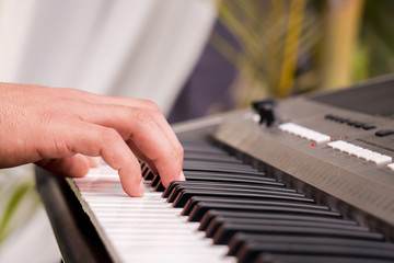 hands pressing keys while playing the electronic piano.