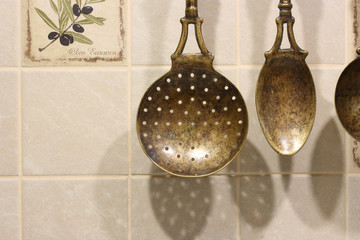 Antique slotted spoon and spoon on ceramic tile wall background