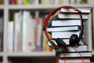 headphones and a stack of books, listening to audio books and traditional reading