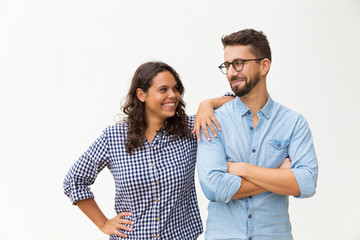 Cheerful couple standing close together, chatting and laughing. Young woman in casual and man in glasses posing isolated over white background. Friendship in couple concept