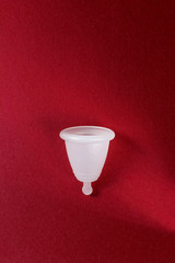 Wall Mural - Menstrual cup on red background, feminine hygiene