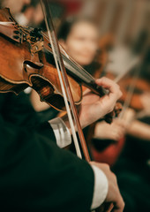 Symphony orchestra on stage, hands playing violin