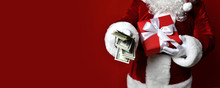 Santa Claus Hold Bunch Of Dollars Money In One Hand And Red Christmas Gift Box Present