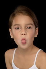 portrait of a little beautiful girl in a white T-shirt on a black background. Emotions