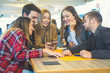 © BooNKer - Group of teenagers hangging out in a bar and using smartphones- Girl showing her friends the new online stuff like photo, video, tik tok- Obsessed in technology concept