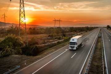 Single lorry truck on a country highway under amazing orange sunset sky