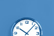 © taniasv - Top of big plain wall clock on trending pastel blue background. Ten o'clock. Close up with copy space, time management or school concept and summer or winter time change, opening hours