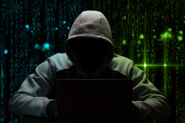 Hacker breaks the digital password, sitting in the dark at the computer on a background of binary code