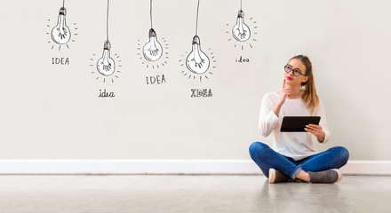 Wall Mural - Idea light bulbs with young woman holding a tablet computer