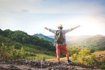 An old man carrying a backpack, hiking and standing on a high mountain He is happy. Senior travel concept