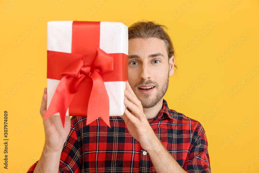 Handsome man with gift on color background. Valentine's Day celebration