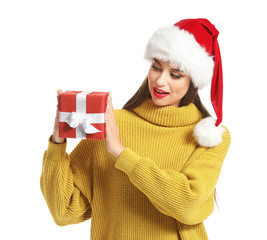 Beautiful young woman in Santa hat and with Christmas gift on white background