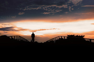 Silhouette of active people on pedestrian bridge against low sunset