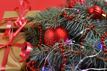 Gifts near the Christmas tree on a red background. Red Christmas balls.